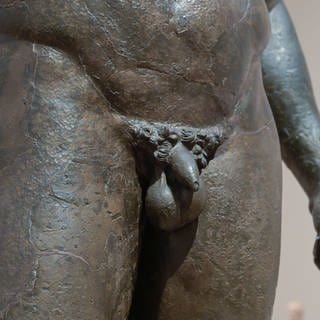 Die Detailaufnahme des Penis einer antiken Bronzestatue