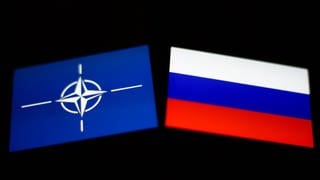 Flaggen der NATO und von Russland: Ausgelöst durch Russlands Krieg gegen die Ukraine wollen die NATO-Länder massiv aufrüsten. Kehrt die atomare Abschreckungspolitik aus Zeiten des Kalten Krieges zurück?
