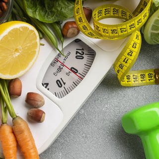 Symbolbild für einen gesunden Lebensstil: Waage, Obst und Gemüse, Gewichte, Maßband
