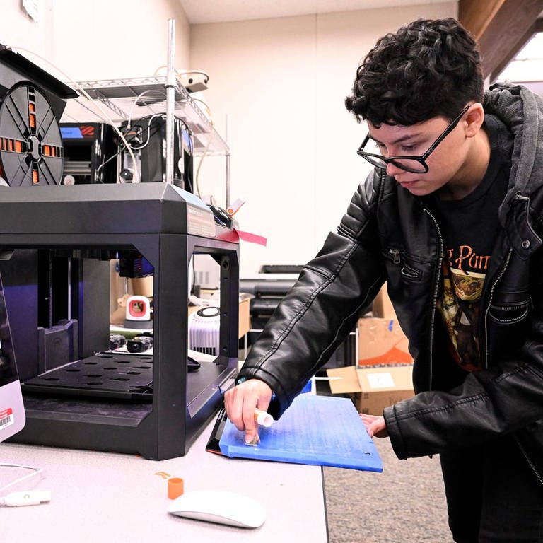 Ein Jugendlicher arbeitet an einen 3D-Drucker.