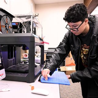 Ein Jugendlicher arbeitet an einen 3D-Drucker.