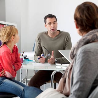 Situation bei einer Beratung; Mutter und Tochter sitzen gegenüber eines Psychologen