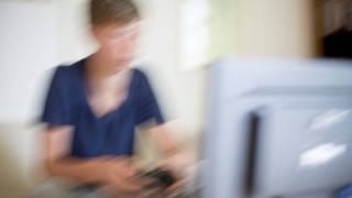 Verschwommenes Bild eines Jungen, der am Computer spielt: Wer kaum stillbare Lust auf Sex verspürt oder fast ununterbrochen Computerspiele spielt, wer besonders lange trauert oder unnütze Dinge hortet, gilt seit 1. Januar 2022 als psychisch krank – gemäß der elften Fassung der internationalen Klassifikation der Krankheiten: ICD-11. 