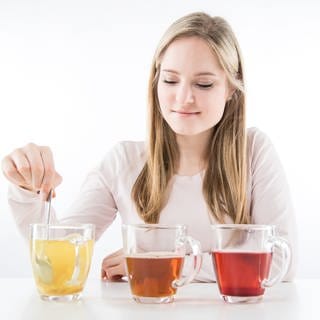 Eine junge Frau sitzt in einem Studio in Hamburg vor mehreren Teetassen