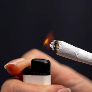 Thema Cannabis-Legalisierung (Symbolbild), Raucherin zündet sich einen Joint an.