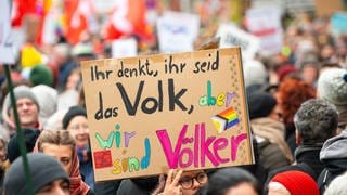 "Ihr denkt, ihr seid das Volk, aber wir sind Völker" steht im Februar 2024 auf einem Schild bei einer Demonstration gegen Rechtsextremismus und die AfD in der Innenstadt von Lübeck. – Wen schließt der Begriff Volk ein und wen aus? Ist die Bezeichnung überhaupt noch zeitgemäß?