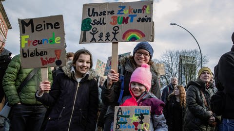 Auf Plakaten steht einer jungen Frau und (ihren) Kindern steht: "Meine Freunde bleiben hier", "Unsere Zukunft soll BUNT sein" und "AfD – Auf keinen Fall, Digga": Demonstration gegen Rechtsextremismus im Februar 2024 in Hamburg. Nach Angaben von "Fridays for Future" nahmen mehr als 50.000 Menschen teil.