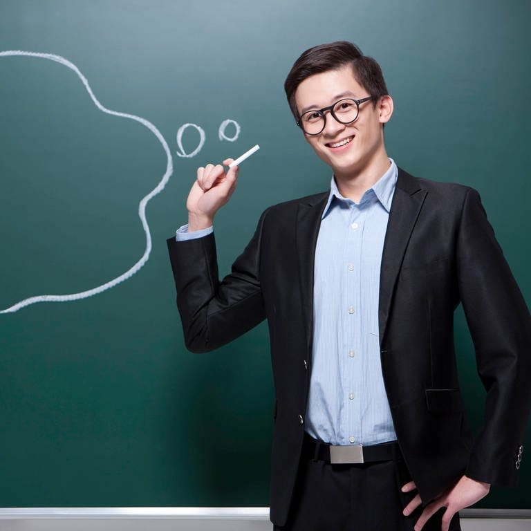 Glücklicher männlicher Chinesischlehrer mit Sprechblase im Klassenzimmer 