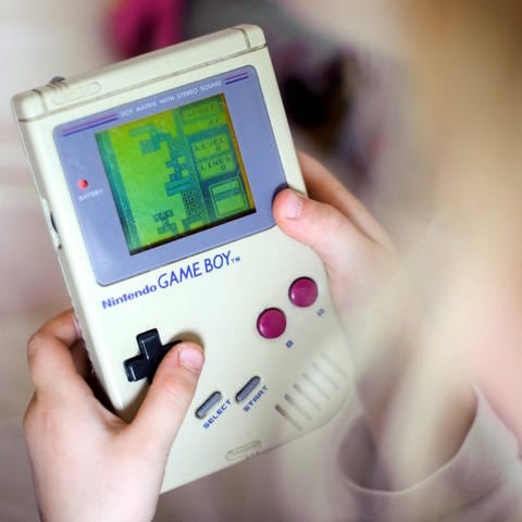 Ein Kind spielt auf einem originalen Game Boy das Spiel Tetris .