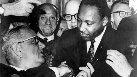 US-Präsident Lyndon B. Johnson reicht Dr. Martin Luther King die Hand, nachdem er am 2. Juli 1964 die Civil Rights Bill unterzeichnet hat. Das Gesetz verbot Diskriminierung an öffentlichen Orten, sah die Integration von Schulen und anderen öffentlichen Einrichtungen vor und machte Diskriminierung am Arbeitsplatz illegal.