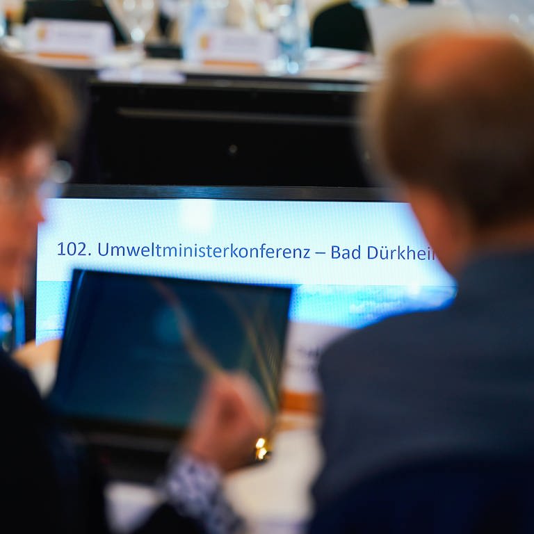 Staatssekretäre und weitere Mitarbeiter sitzen beim Auftakt der Umweltministerkonferenz (UMK) von Bund und Ländern unter dem Vorsitz von Rheinland-Pfalz an einem Konferenztisch vor einem großen Bildschirm mit der Aufschrift «102. Umweltministerkonferenz».