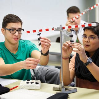 Schüler in einer Schulklasse experimentieren in Physik zum Thema Hebelwirkung
