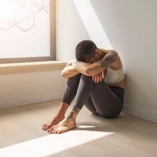 Symbolfoto: Traurige Frau sitzt auf dem Boden am Fenster