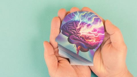 Graphik eines Kopfes mit "Kopfgewitter" liegt auf geöffneten Handflächen: Epileptische Anfälle sind seit Jahrtausenden bekannt. Heute ermöglichen chirurgische Eingriffe, Gentherapien oder Hirnschrittmacher vielen Betroffenen einen normalen Alltag.