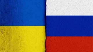 Nationalflaggen der Ukraine sowie von Russland im Anschnitt sowie einem Riss zwischen beiden Parteien.