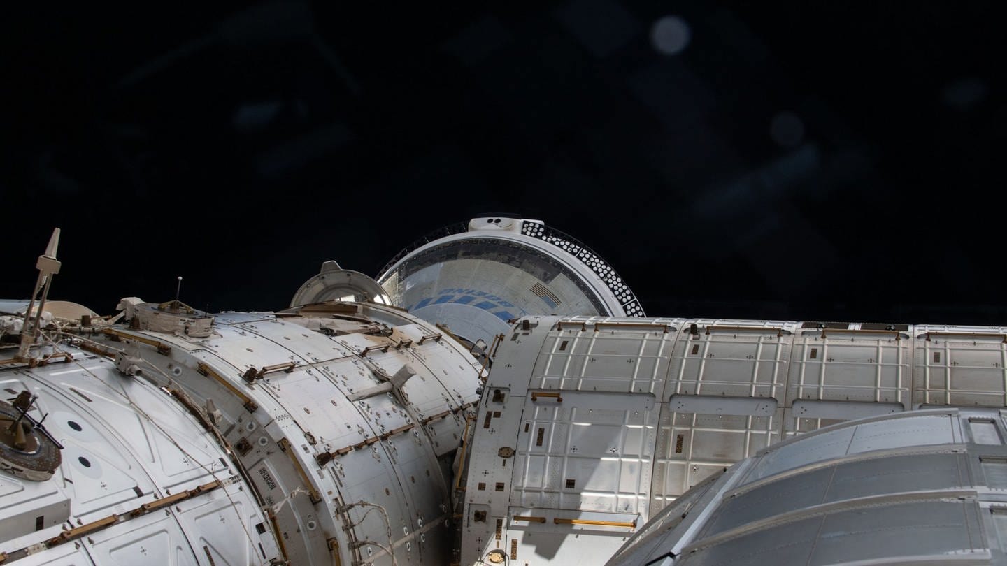Auf diesem Archivfoto überblickt dieser Blick aus einem Fenster der Kuppel einen Teil des Internationalen Weltraums und zeigt das teilweise verdeckte Starliner-Raumschiff von Boeing, das an der vorderen Öffnung des Harmony-Moduls angedockt ist.