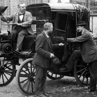 Daimler Riemenwagen Viktoria mit den Herren Möwes, Wilhelm Bauer und Paul Daimler (von links), um 1897. Das Bild ist vermtulich auf dem Fabrikhof der Cannstatter Fabrik entstanden.