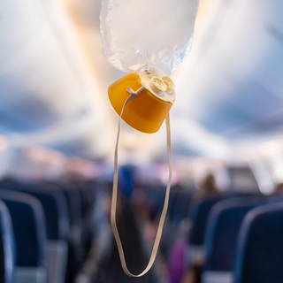 Sauerstoffmaske fällt aus dem Deckenfach eines Flugzeugs. 