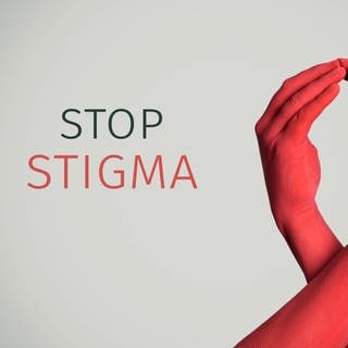 Nahaufnahme der Arme zweier rot bemalter Männerarme, die ein rotes Band für die HIVAIDS-Aufklärung bilden, und der Text Stop Stigma vor einem cremefarbenen Hintergrund 