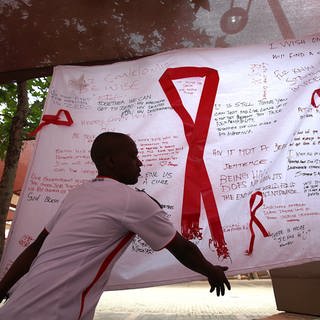 Ein Mann hängt ein Banner am "Wits Reproductive Health and HIV Institute" anlässlich des Welt-Aids-Tages mit dem Kampagnenmotto „Getting to Zero“ in Johannesburg, Südafrika auf. (Archivfoto)
