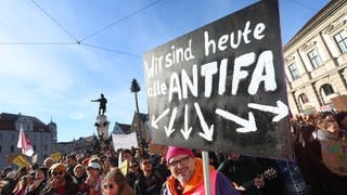Ein Demonstrant hält im Februar 2024 auf dem Rathausplatz in Augsburg ein Schild mit der Aufschrift "Wir sind heute alle ANTIFA". Mit der Demonstration wollen die Teilnehmer ein Zeichen des Widerstands gegen rechtsextreme Umtriebe setzen.