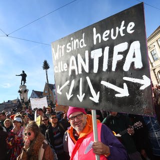 Ein Demonstrant hält im Februar 2024 auf dem Rathausplatz in Augsburg ein Schild mit der Aufschrift "Wir sind heute alle ANTIFA". Mit der Demonstration wollen die Teilnehmer ein Zeichen des Widerstands gegen rechtsextreme Umtriebe setzen.