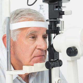 Nahaufnahme eines Optikers, der Sehtests für einen älteren Patienten durchführt