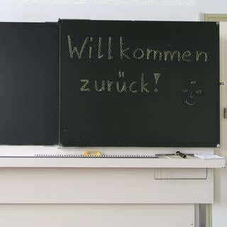 Auf einer Wandtafel steht "Willkommen zurueck!