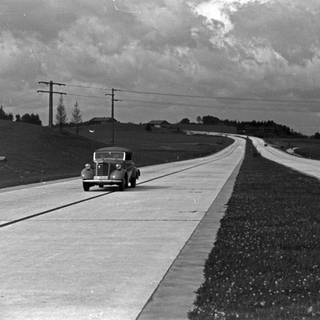 In den 1930ern unterwegs auf der Reichsautobahn: ein einsamer PKW: Mit der Möglichkeit, große Entfernungen schnell zu überwinden, spielen Autobahnen bis heute eine wichtige Rolle für die infrastrukturelle und wirtschaftliche Entwicklung. Doch mit dem steigenden Bewusstsein für Umwelt- und Klimaschutz gerät eine Verkehrspolitik, die auf Autobahnen und Individualverkehr setzt, zunehmend in die Kritik.