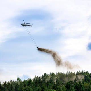 Helicopter beim ausbringen von feingemalenem Kalkstein und Holzasche.