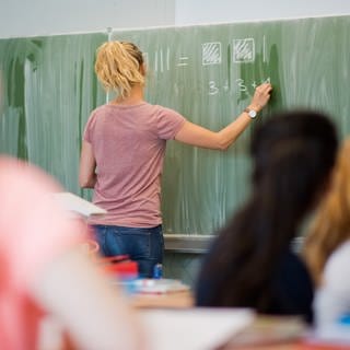 Eine junge Lehrerin schreibt an eine Schultafel