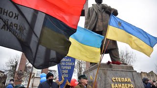 Menschen mit Fahnen in der Nähe des Denkmals für Stepan Bandera in Lwiw während der Feierlichkeiten zu dessen 113. Geburtstag am 1. Januar 2022