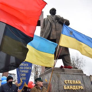 Menschen mit Fahnen in der Nähe des Denkmals für Stepan Bandera in Lwiw während der Feierlichkeiten zu dessen 113. Geburtstag am 1. Januar 2022