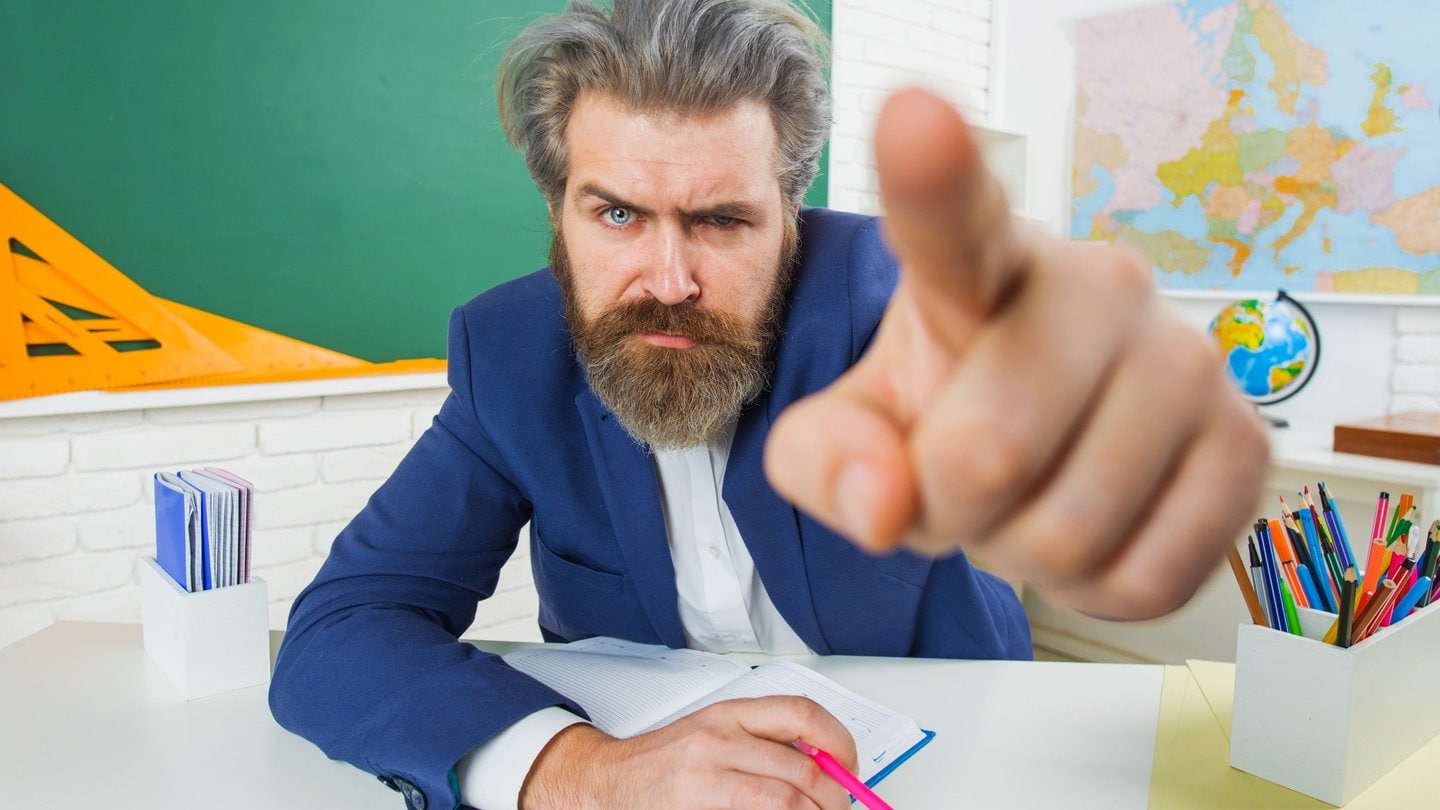 Wütender Lehrer zeigt mit dem Finger: Was eine gute Lehrkraft ausmacht, wird laufend neu definiert. Doch was passiert, wenn Lehrerinnen und Lehrer im Umgang mit Kindern und Jugendlichen nicht zurechtkommen, immer wieder scheitern oder gar versagen?