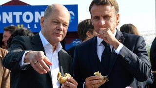 Bundeskanzler Olaf Scholz (SPD) und Frankreichs Präsident Emmanuel Macron (rechts) essen gemeinsam in Blankenese an der Elbe ein Fischbrötchen. Das deutsche und das französische Kabinett trafen sich im Oktober 2023 in der Hansestadt zu einer zweitägigen Klausur. Gemeinsames Speisen ist eines der ältesten Instrumente der Diplomatie, um Verständigung und Kooperation zu fördern. Macron schien nicht ganz so begeistert von der norddeutschen Spezialität.