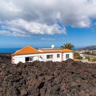 Auf der Kanarischen Insel La Palma ist ein Haus von Lava eingeschlossen. Der Vulkanausbruch auf La Palma 2021 dauerte vom 19. September bis zum 13. Dezember 2021. Was kann die Wissenschaft beitragen, um Menschen und Siedlungen vor Vulkanausbrüchen zu schützen?