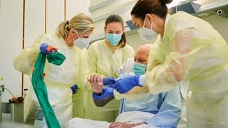 Eine Medizinproduktberaterin im Bereich Narbentherapie, eine ukrainische Rehabilitationärztin und Oberärztin Jenny Dornberger (rechts), Zentrum für Schwerbrandverletzte mit Plastischer Chirurgie im Unfallkrankenhaus Berlin versorgen einen Soldaten aus der Ukraine, der Brandverletzungen erlitten hat. Die Nachsorge brandverletzter Patienten dauert oft jahrelang. Ärzte aus dem Unfallkrankenhaus teilen ihr Fachwissen mit ukrainischen Ärzten und Ärztinnen, die hier hospitieren. 