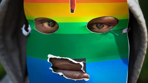 Ein kenianischer Unterstützer der LGBT-Gemeinschaft ist mit einer Regenbogenflagge maskiert und protestiert 2014 gegen Ugandas Anti-Homosexuellen-Gesetz vor dem ugandischen Hochkommissariat in Nairobi, Kenia. Über die Hälfte der afrikanischen Staaten verbietet Homosexualität, in Uganda kann sie sogar mit dem Tod bestraft werden.