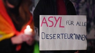 Mahnwache für Frieden in Tübingen auf dem Holzmarkt im Februar 2022. Auf einem Banner steht "Asyl für alle Deserteur*innen". Viele Deserteure und Wehrdienstentzieher aus Russland und der Ukraine kommen derzeit nach Deutschland und bitten um Asyl. Wie soll die deutsche Politik mit ihnen umgehen?