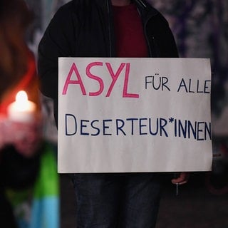 Mahnwache für Frieden in Tübingen auf dem Holzmarkt im Februar 2022. Auf einem Banner steht "Asyl für alle Deserteur*innen". Viele Deserteure und Wehrdienstentzieher aus Russland und der Ukraine kommen derzeit nach Deutschland und bitten um Asyl. Wie soll die deutsche Politik mit ihnen umgehen?