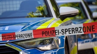 Rot-weißes Absperrband mit der Aufschrift "Polizei-Sperrzone", dahiner Polizeiautos: Die Anzahl psychisch erkrankter Menschen in Deutschland steigt seit Jahren. Auch die psychischen Krisen nehmen zu. Kommt es deswegen zu einem Polizeieinsatz, kann das für Betroffene gefährlich sein, denn nicht selten enden solche Situationen tödlich. 