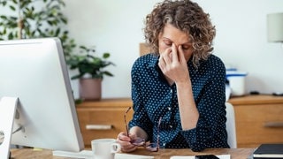 Müde Geschäftsfrau sitzt am Schreibtisch im Büro