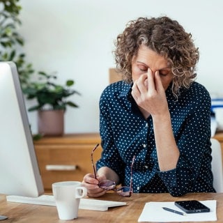 Müde Geschäftsfrau sitzt am Schreibtisch im Büro