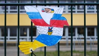 Friedenstaube in den russischen und ukrainischen Farben an einer Schule in Berlin: Russlands Angriff auf die Ukraine fordert die Schulen heraus. Kinder äußern Ängste und stellen Fragen zum Krieg. Traumatisierte Flüchtlingskinder aus der Ukraine treffen auf russischstämmige Mitschüler.