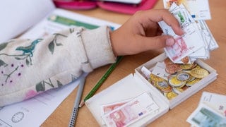 Das Wissen von Kindern und Jugendlichen über Finanzen ist dünn und sie wünschen sich selbst bessere Aufklärung: Eine Schülerin einer 2. Klasse rechnet im Klassenzimmer einer Grundschule mit Spielgeld