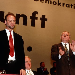 Der geschlagene und abgewählte Rudolf Schwarping (links) nimmt den Applaus von Oskar Lafontaine entgegen auf dem Parteitag der SPD am 16.11.1995 in Mannheim. In der Mitte Johannes Rau.