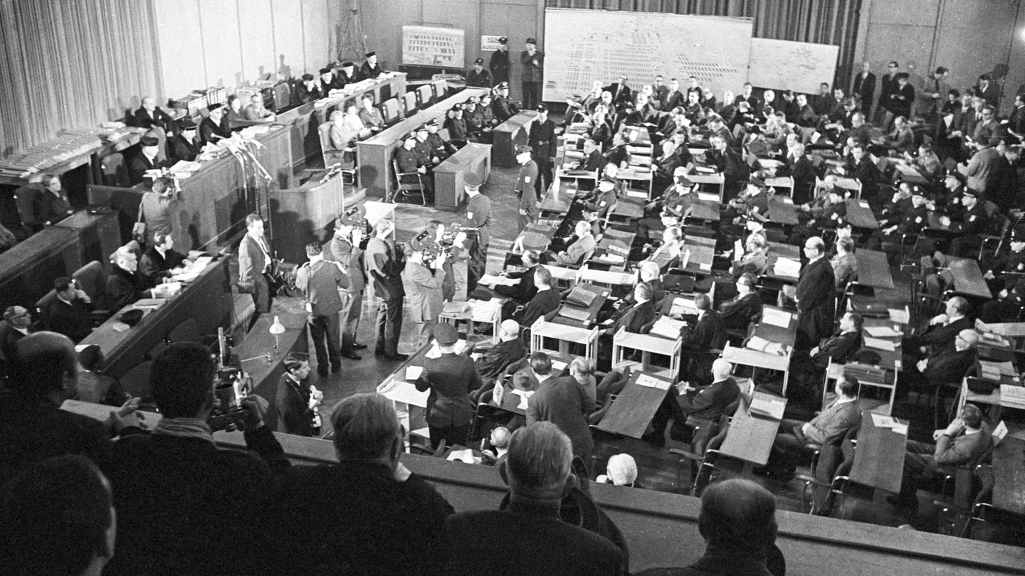 Blick in den Saal des Frankfurter Rathauses, wo 22 ehemalige Wachen und Beamte (rechts abgebildet mit ihren Anwälten und Polizisten) des Konzentrationslagers Auschwitz vor Gericht gestellt wurden. Sie waren für die Tötung von mehr als 2 1/2 Millionen Menschen im Lager verantwortlich. (Aufnahme vom 20. Dezember 1963)