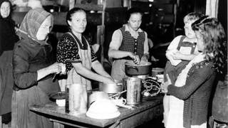 Frauen bereiten 1948 an einem Tisch im bayerischen Flüchtlingslager Allach Mahlzeiten zu