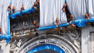 Gebäudekletterer haben mit der Verhüllung des Triumphbogens (Arc de Triomphe) begonnen. Bis zum 18. September 2021 soll die Verhüllung vollendet sein – und damit ein Lebenstraum des Künstler-Ehepaars Christo und Jeanne-Claude, dessen Erfüllung beide jedoch nicht mehr miterleben können.