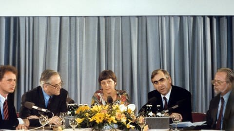 Der Finanzminister der DDR, Walter Romberg (2.v.l.) und der bundesdeutsche Finanzminister Theo Waigel (2.v.r.) geben im Internationalen Medienzentrum im Ministerratsgebäude in Ost-Berlin am 1. Juli 1990 eine Pressekonferenz zur Währungunion. In der Mitte sitzt Angela Merkel, stellvertretende Regierungssprecherin der DDR.